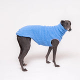 Greyhound dog wearing Snootly fluffy reversible sleeveless sweater in cornflower blue on white background