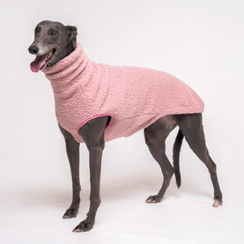 Greyhound dog wearing Snootly fluffy reversible sleeveless sweater in marshmallow pink on white background