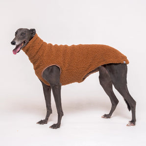 Greyhound dog wearing Snootly fluffy reversible sleeveless sweater in caramel on white background