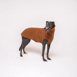 Greyhound dog wearing Snootly fluffy reversible sleeveless sweater in caramel on white background