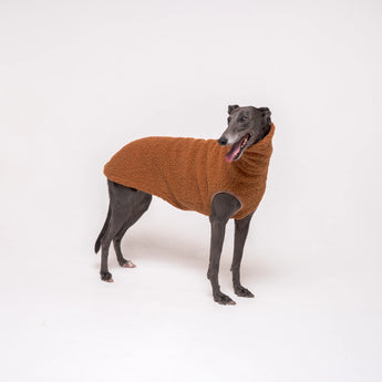 Greyhound dog wearing Snootly fluffy reversible sleeveless sweater in caramel on white background