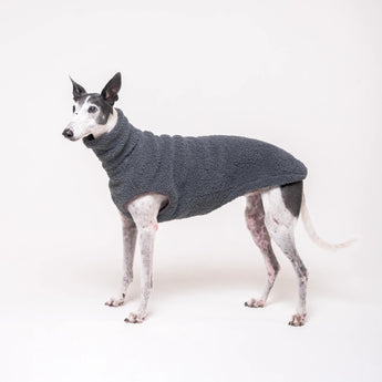 Greyhound dog wearing Snootly fluffy reversible sleeveless sweater in charcoal grey on white background