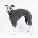 Whippet wearing a fluffy reversible onesie in charcoal standing left side