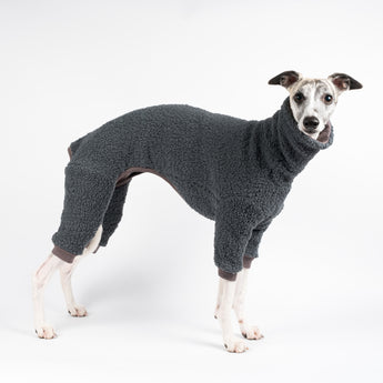 Whippet wearing a fluffy reversible onesie in charcoal standing right side